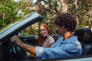 Couple enjoying a drive in a convertible in summer road