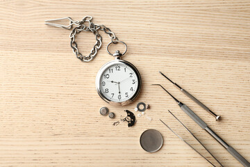 Watch and tools for repair on wooden background