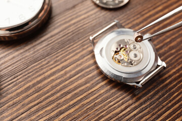 Clockmaker repairing broken watch at table, closeup