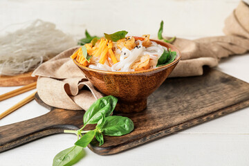 Bowl with tasty rice noodles and shrimps on table