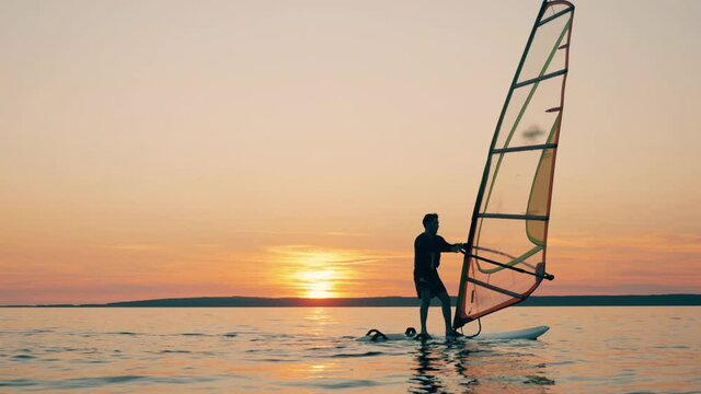 A man is managing a sail of a windsurf board while floating