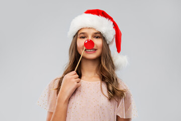 christmas party, holidays and photo booth concept - happy smiling teenage girl in santa helper hat...