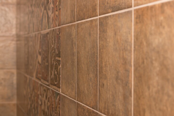 Bathroom wall covered with square tiles, warm brown dark beige color