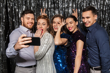 celebration, technology and holiday concept - happy friends taking selfie by smartphone at party