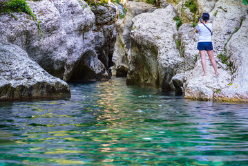 Calm river with clear water between white rocks. Tourist takes a
