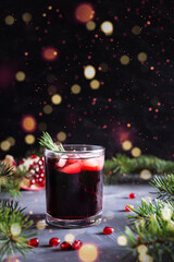 Pomegranate Christmas cocktail with rosemary, champagne, club soda on black table with bokeh lights. New year drink