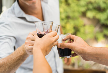 Wine toasting at the party in the countryside terrace. People having fun drinking wine together, closeup o the hands holding and clinking the wine glasses.