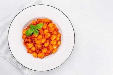 Gnocchi - potato dumplings  with tomato and meat sauce. Italian dish. Decorated with basil. White background. Flat lay.