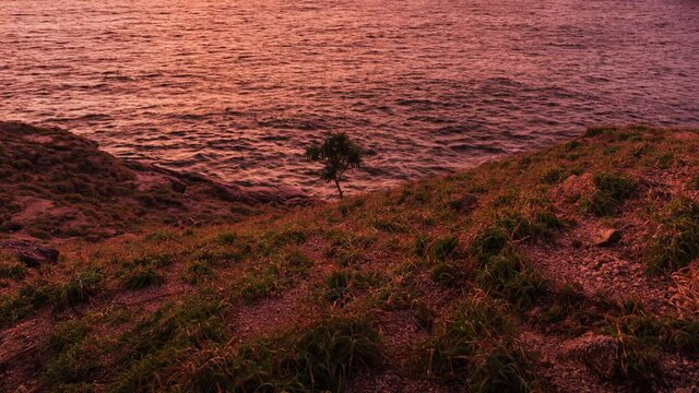 beautiful sunset on green grass coastline 4k time lapse, laem krating viewpoint at Phuket Thailand 