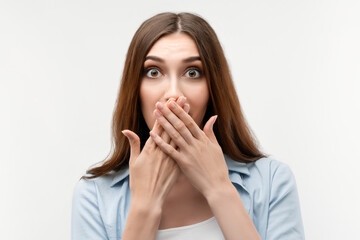 Image of young scared woman covering her mouth with hands. Fright, phobia, horror and facial expression concept