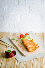 Butterfly ebi furai shrimp served with tomato and lettuce on a wooden chopping board along with ketchup