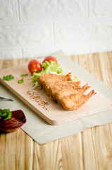 Butterfly ebi furai shrimp served with tomato and lettuce on a wooden chopping board along with ketchup