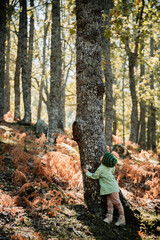 Fototapeta premium Little girl in an autumn forest among ferns