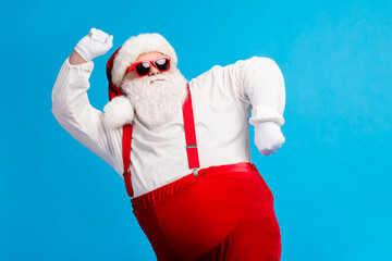Photo of old man grey beard dance having fun raise hand fists wear santa claus x-mas costume cap...
