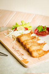 Butterfly ebi furai shrimp served with tomato and lettuce on a wooden chopping board along with ketchup