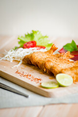 Butterfly ebi furai shrimp served with tomato and lettuce on a wooden chopping board along with ketchup
