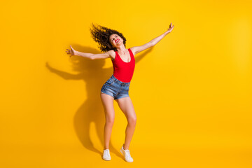 Fototapeta na wymiar Full length body size photo of funny hipster girl with curly hairdo dancing at party singing wearing jeans mini shorts tank-top isolated on vivid yellow color background