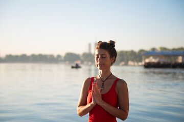 Fototapeta na wymiar Woman meditating and practising yoga during sunrise in paddle board