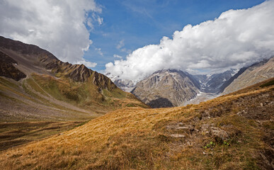 Panorama of a Alpine mountain valley and peaks. High mountain peaks and a glacier and water falls on the Italian side of the Mont Blanc Massive.