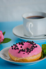 Pink round donut at bright blue background with coffee glass
