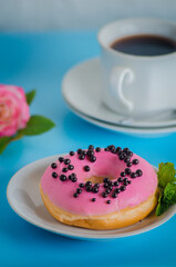 Pink round donut at bright blue background with coffee glass
