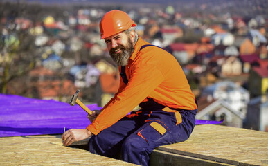 handsome builder use hammer. professional master repair roof. Flat roof installation. roofing felt....