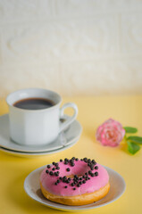 Obraz na płótnie Canvas Pink round donut at bright yellow background with coffee glass 