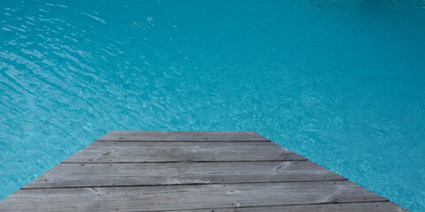 wooden board around the blue water of swimming pool