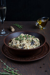 Traditional creamy risotto or Italian arborio rice dish cooked with broth containing mushrooms, onion, white wine, olive oil and parmesan cheese on dark brown wooden background. Vertical orientation