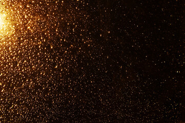 Fototapeta na wymiar Water drops on a window glass after the rain. Gold sunset or sunrise on dark background.