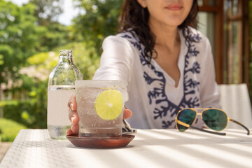 Woman hand reachinf glass of healthy nutrition of sparkling water.