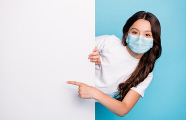 Close-up portrait cheerful cheery wavy-haired girl demonstrating empty space ad advert point finger covid outbreak news wear medical mask isolated bright shine blue color background - Powered by Adobe