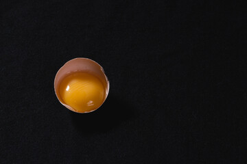 Raw chicken, egg yolk close up, black background