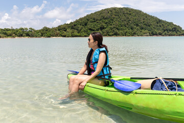 Fototapeta na wymiar Tourist woman sitting on kayak lookign at beautiful tropical beach on vacation.
