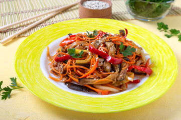 Korean eggplants. Spicy vegetable salad with eggplant, bell peppers, carrots, onions on a plate on a bright background.