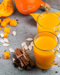Natural homemade spicy autumn pumpkin juice in glass mugs on a gray table