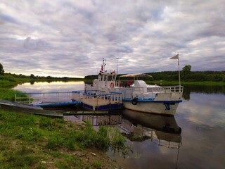 Fototapeta premium White old pleasure boat on the river bank at sunset