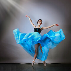 Ballerina on a gray background in a fluttering dress