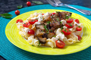 Pasta with grilled eggplant, cherry tomatoes, goat cheese and herbs. Delicious warm salad. Proper nutrition.