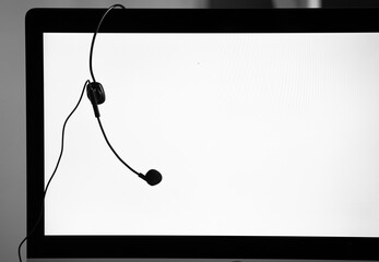 Headphone headset hanging on edge of blank computer screen monitor. The idea for call center work and take a break during working time. - 377852709