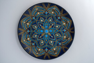 Decorative ceramic plate with black, blue and golden colors, painted plate on white background, dot painting
