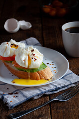 Sandwich with poached egg, tomatoes and cucumbers on a wooden background