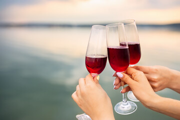 female hands with glasses of red champagne making toast