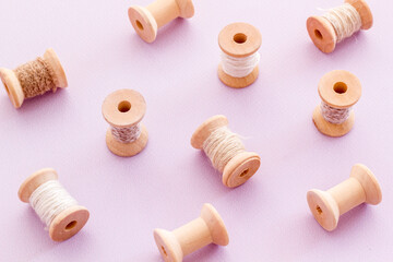 Wooden spools of thread for sewing on lilac background