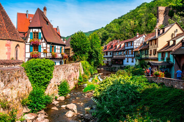 Colorful facades and flowers overlooking the river in the village of Kaysersberg in Alsace, France