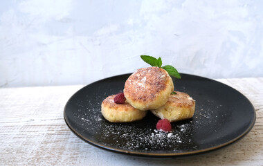 Сheese pancake on the black plate on the wood background