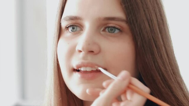 Professional make up artist applying liquid lipstick on lips