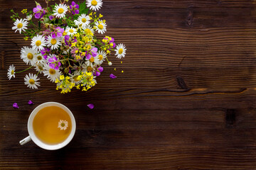 Wild flowers bouquet with cup tea on a table, top view