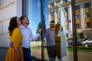 A date between a young girl and a guy on a Sunny summer day. Young beautiful couple on walk in the city. Man and woman at a love meeting with hugs and kisses outdoors