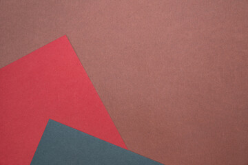 Fototapeta premium Three sheets of colored paper on a brown background. Red, green. Minimalistic composition. Background for text or design. Empty right side. Top view